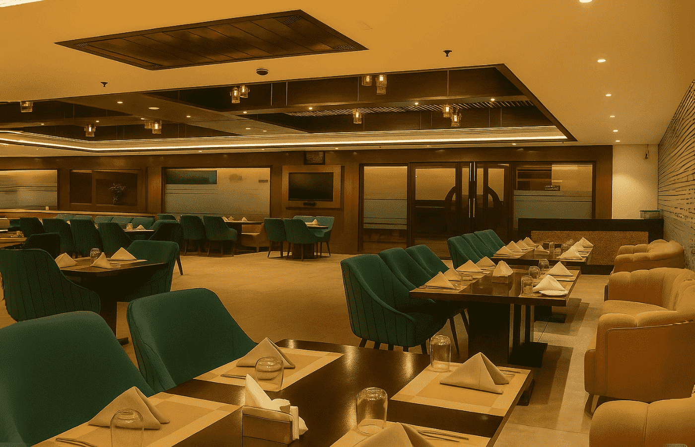 Spacious and modern dining area at BlueFin Restaurant featuring teal chairs, beige sofas, and a stylish ceiling design.