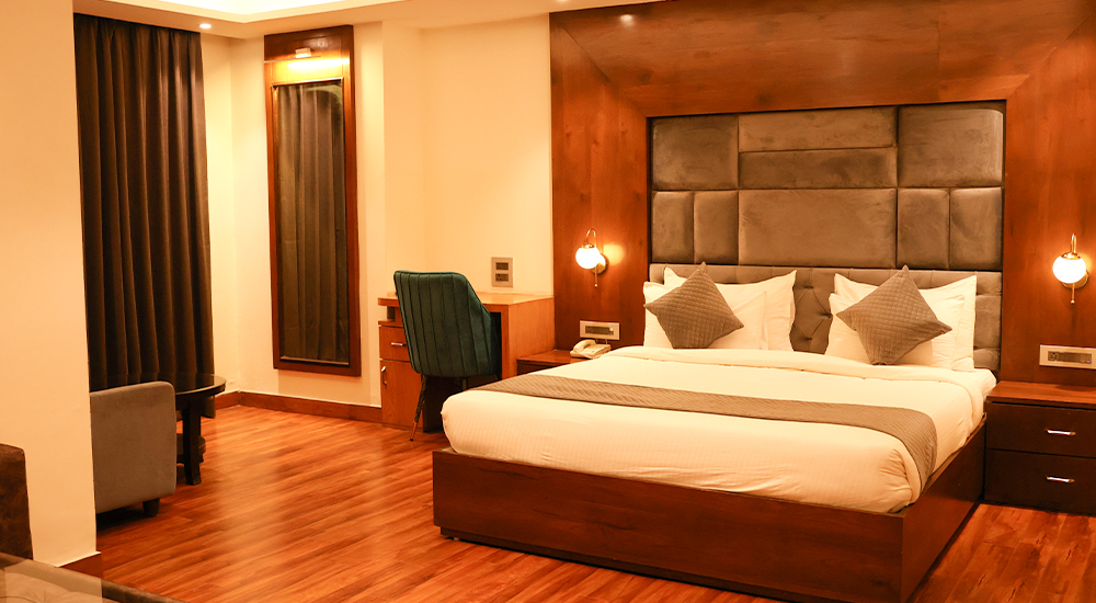 Spacious deluxe hotel room with modern wooden interiors and comfortable king-size bed in Dehradun