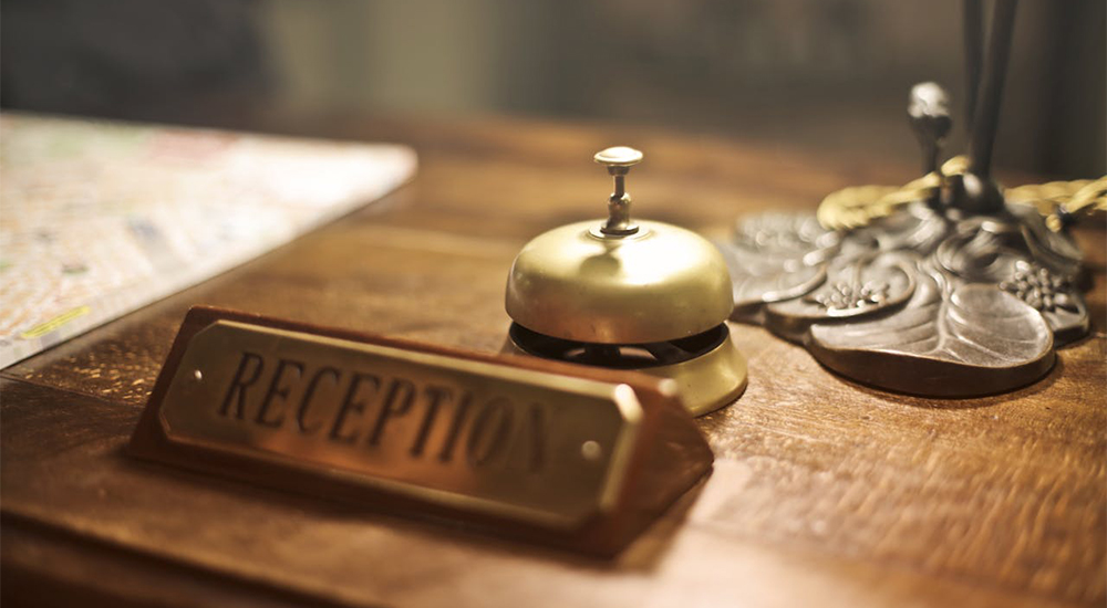 Emerald Grand Hotel reception desk with service bell representing professional guest support and warm hospitality