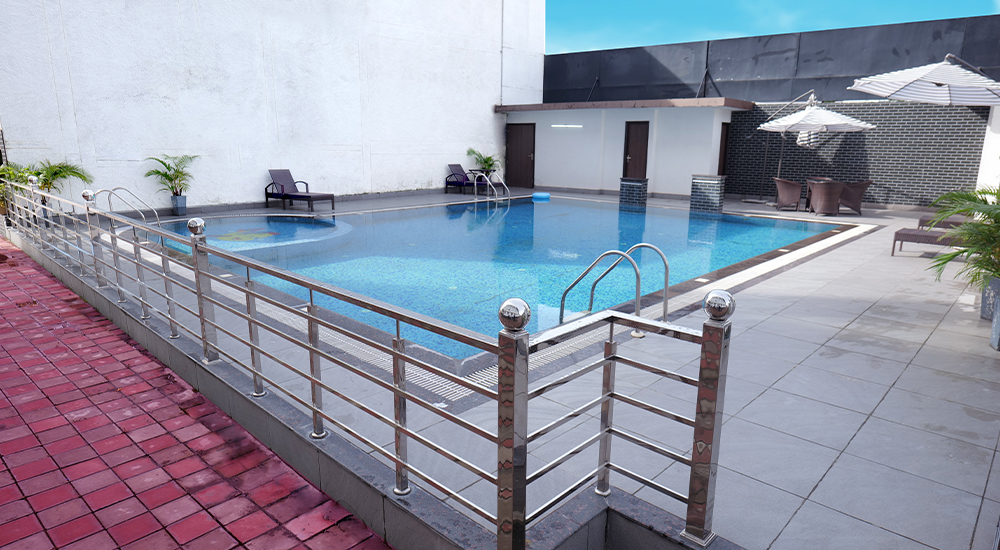 Outdoor swimming pool with lounge chairs and modern amenities at a luxury hotel in Dehradun