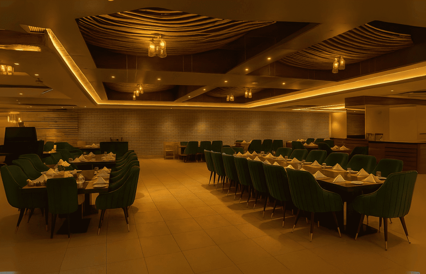 Large, warmly lit dining hall at BlueFin Restaurant with elegant green chairs, neatly arranged tables, and ambient ceiling lighting.